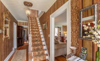 a foyer with a staircase leading to the second floor , which is decorated with brown and gold wallpaper at Van Winkle Inn