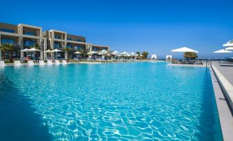 a large outdoor pool surrounded by lounge chairs and umbrellas , with a building in the background at Myrion Beach Resort & Spa - Adults Only