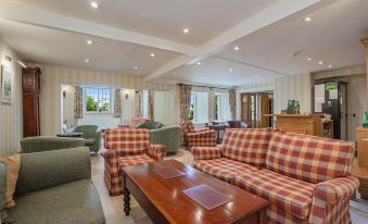 a spacious living room with multiple couches and chairs arranged in various positions , creating a cozy atmosphere at Castle of Comfort Hotel