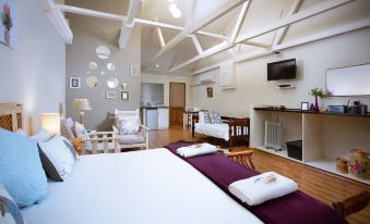 a spacious bedroom with two beds , a couch , and a tv . also a dining table in the room at Morning Glory Cottages