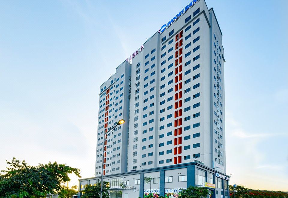 a tall building with a blue and white facade , located in a city setting with trees at Tien Loc Palace Hotel