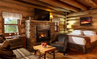 a cozy living room with a fireplace , wooden walls , and a flat - screen tv mounted on the wall at Justin Trails Resort