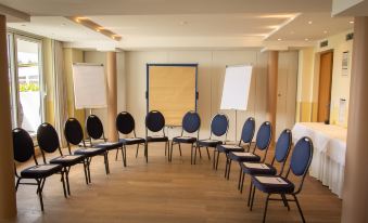 a conference room set up for a meeting , with rows of chairs arranged in a semicircle at Seehotel Leoni