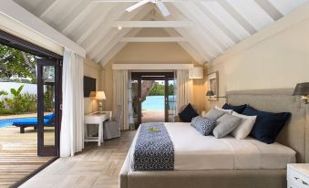 a luxurious bedroom with a king - sized bed , a ceiling fan , and a door leading to a pool area at Warwick le Lagon Resort & Spa, Vanuatu