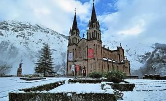 a large stone church with two spires is surrounded by snow - covered mountains and a red banner at Hotel Cerro La Nina