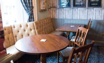 a small restaurant with wooden tables and chairs , as well as a dining area with a table and bench at The Green Dragon at Bedale