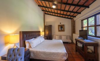 a hotel room with a king - sized bed , a flat - screen tv , and a dining table at Quinta San Carlos