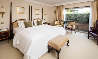 a large bedroom with a white bed , wooden chairs , and sliding glass doors leading to an outdoor area at The Atlantic Hotel