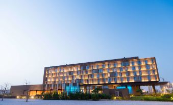 a large hotel building with many windows and a blue sign is lit up at night at Radisson Hotel, Dakar Diamniadio