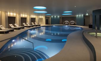 an indoor swimming pool with blue lights and white lounge chairs , creating a relaxing atmosphere at Leonardo Hotel and Conference Venue Hinckley Island