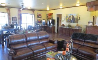 a spacious living room with a brown leather couch and a large flat screen tv mounted on the wall at Hotel Texas Cuero