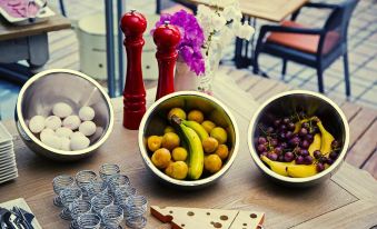 a dining table with a variety of fruits , including bananas , oranges , and grapes , as well as a pizza at Upper House Hotel