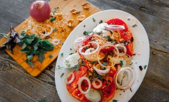 a white plate filled with a colorful salad , surrounded by various condiments and other food items at Laguna Beach Club Bazaleti Lake