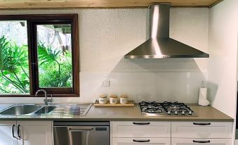 a modern kitchen with stainless steel appliances , including a stove , oven , and refrigerator , along with a sink and cabinets at William Bay Cottages