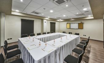 a conference room with a large table surrounded by chairs , and a tv mounted on the wall at City Express by Marriott Cdmx la Villa