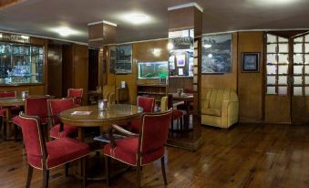 a dining room with a wooden table surrounded by chairs , and a fish tank in the background at Hotel Astoria