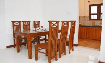 a wooden dining table surrounded by six chairs , with a kitchen in the background filled with appliances at Heaven Rest