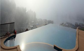 a man standing on the edge of a swimming pool with a foggy background at Samprasob Resort