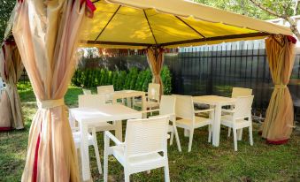 an outdoor dining area with white tables and chairs , surrounded by a lush green lawn at Garden Inn Resort Sevan