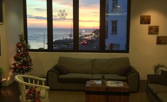 a living room with a couch , coffee table , and window overlooking the ocean at sunset at The Oikos Hotel