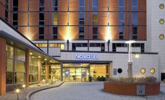 a modern hotel building with a large sign above the entrance , and a parking lot outside the building at Novotel Leeds Centre