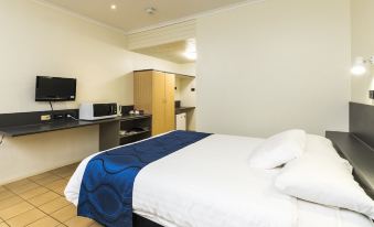 a hotel room with a large bed , a desk , and a television . also a bathroom visible in the room at Albatross Bay Resort