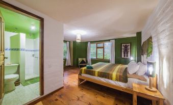 a bedroom with a large bed , wooden floors , and a glass door leading to a bathroom at La Casa Verde