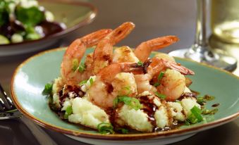 a plate of shrimp and mashed potatoes with a brown sauce , garnished with green onions at Atlanta Marriott Peachtree Corners