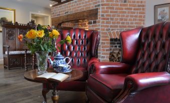 a cozy living room with a leather couch , a coffee table , and a vase of flowers at The Nags Head