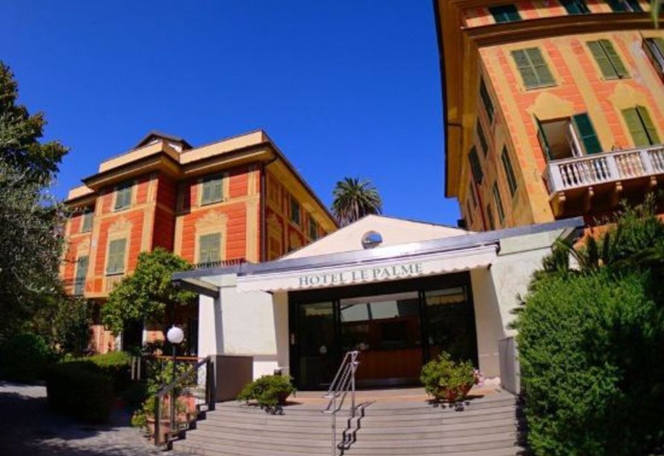 a building with two balconies , one on the left and one on the right , surrounded by lush greenery at Hotel Le Palme