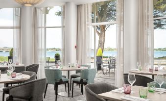 a dining room with white walls , large windows , and a view of the lake through a glass door at Langstone Quays Resort
