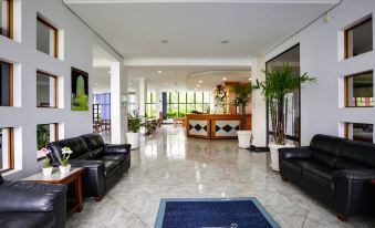 a spacious lobby with black leather couches , a reception desk , and potted plants , giving it an inviting atmosphere at Hotel San Isidro