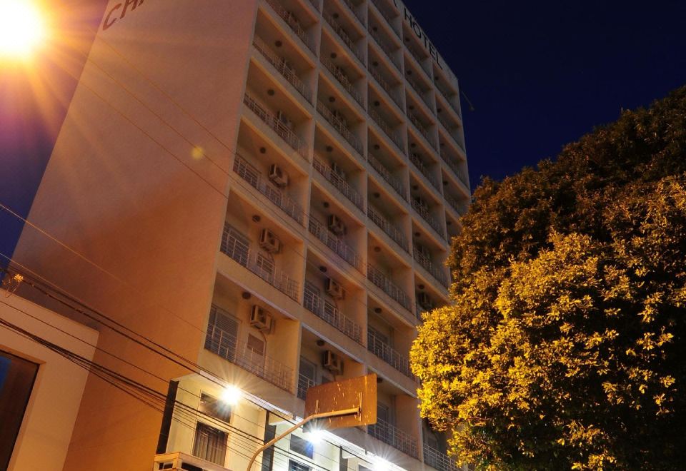 "a tall hotel building with a sign that reads "" hotel sapporo "" is lit up at night" at Hotel Nacional Inn Araçatuba