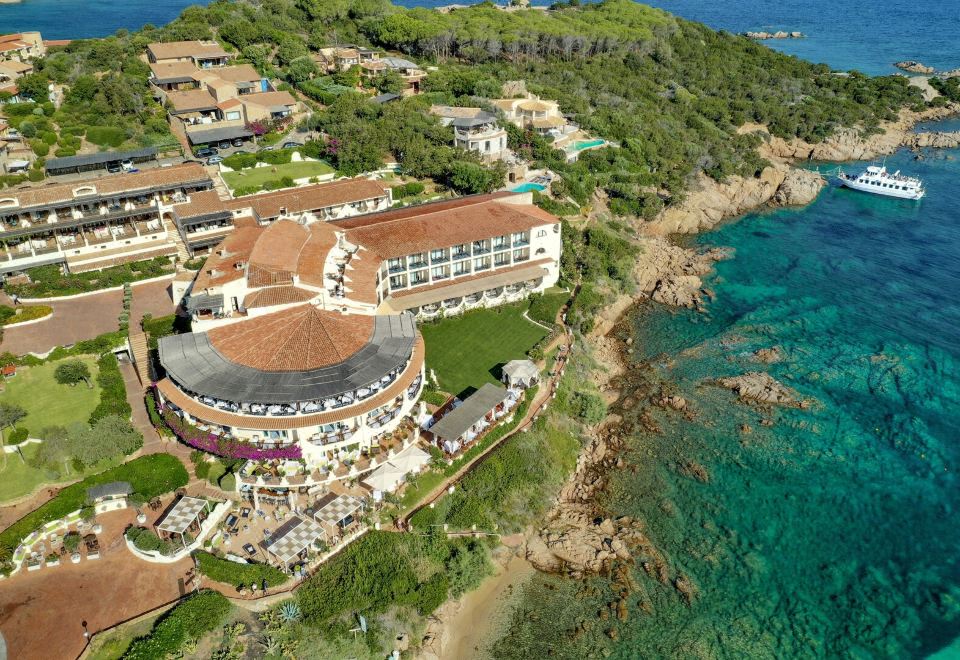 aerial view of a resort on the coast , with a large building and pool visible at Club Hotel Baja Sardinia