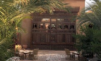 a courtyard with a stone floor , a wooden bench , and a brick wall in the background at Al Moudira Hotel