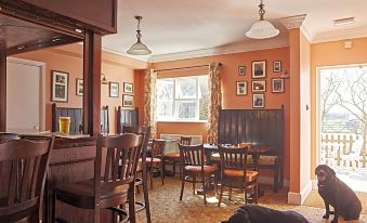 a cozy living room with a dining table , chairs , and a dog laying on the floor at Corse Lawn House Hotel