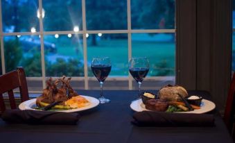 a dining table with two plates of food and two glasses of wine , set against a window at Mountain Cove Farms Resort