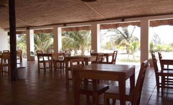 a dining area with wooden tables and chairs , surrounded by a patio with palm trees at Hotel Maya