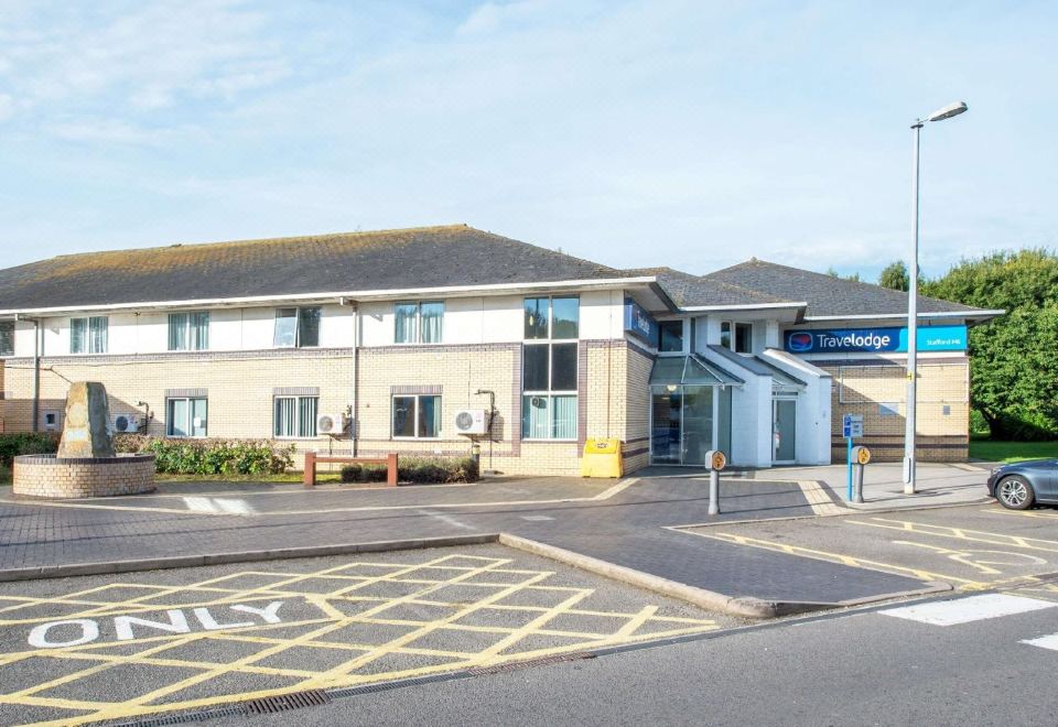 "a modern building with a sign that says "" travelodge "" and a car parked in front of it" at Travelodge Stafford M6