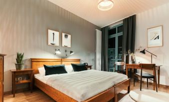 a modern bedroom with a wooden bed , black pillows , and a window view of the city at Hotel Esplanade