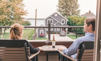 a man and a woman are sitting at a table on a patio , enjoying a glass of wine and looking out at the water at Inn on Water Street