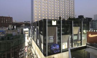 A view of an office building in the corner of Hong Kong, taken from ground level and looking up at Solaria Nishitetsu Hotel Seoul Myeongdong