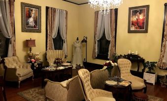 a luxurious living room with white walls , gold trim , and elegant furniture , including sofas , chairs , and a dining table at Whole Hearts Bed and Breakfast