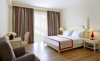 a large bed with a red and white striped blanket is in the middle of a room with wooden floors at Alkyon Resort Hotel & Spa