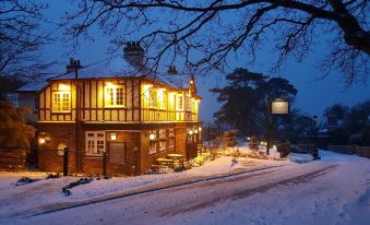 a snow - covered street with a house illuminated by yellow lights , creating a warm and inviting atmosphere at The Fishbourne
