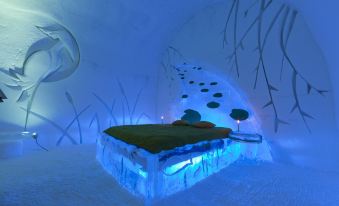 a bed is made of snow and has blue lights , while the walls and ceiling have ice at Hotel de Glace (Ice Hotel)