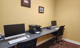 a desk with two computer monitors and a printer is set up in an office area at Best Western White House Inn