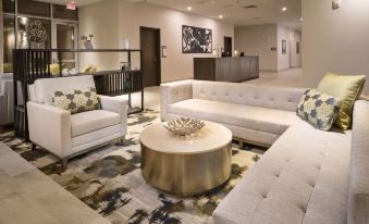 a modern living room with white sofas , a round coffee table , and a large abstract painting on the wall at Best Western Plus Executive Residency Austin