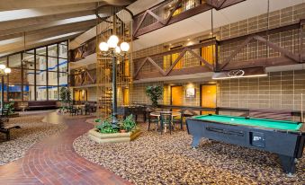 an indoor pool area with a pool table in the center , surrounded by chairs and tables at Best Western Plus Longbranch Hotel  Convention Center