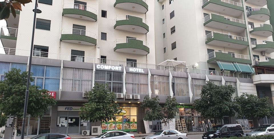 a city street with a tall apartment building and a car parked on the side of the road at Comfort Hotel